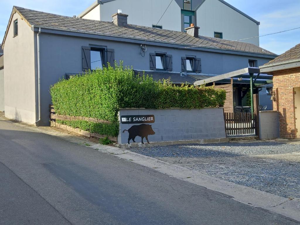 um cão parado ao lado de um sinal em frente a uma casa em le sanglier em Bertogne
