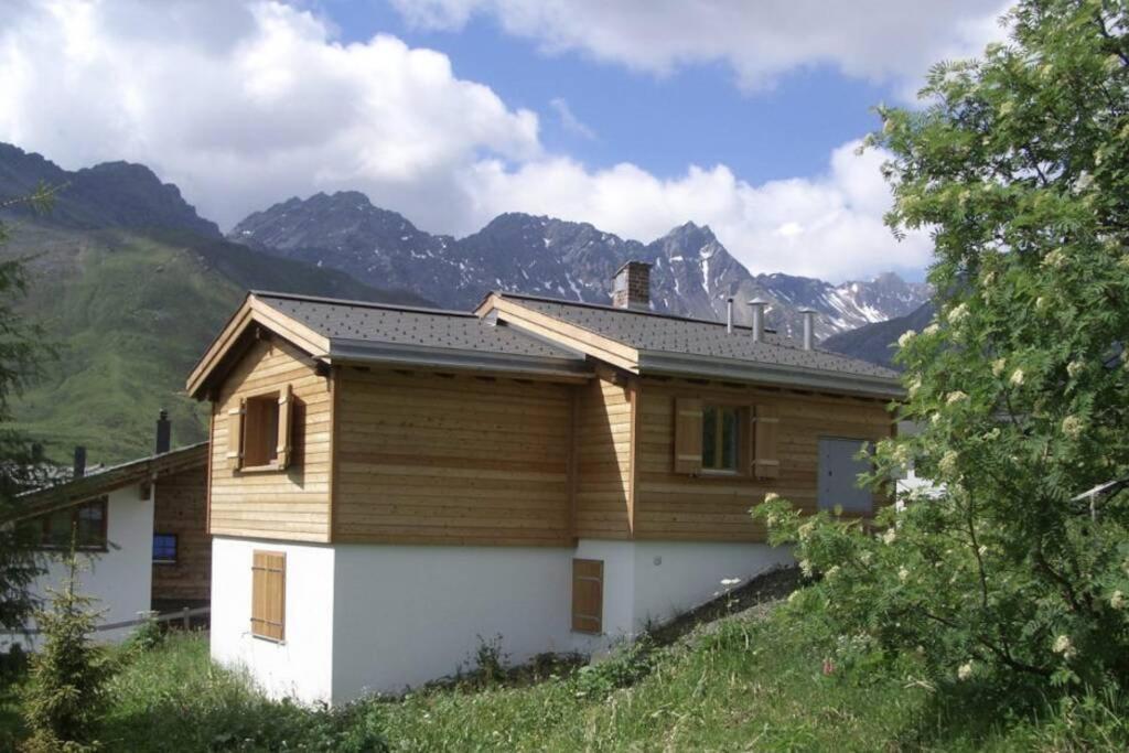 a house on a hill with mountains in the background at Chalet Höckli Wohnung 1. in Arosa