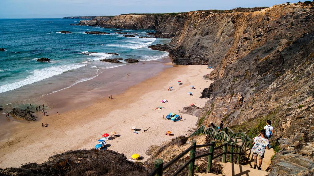 a group of people on a beach near the ocean at Breathe In in Zambujeira do Mar