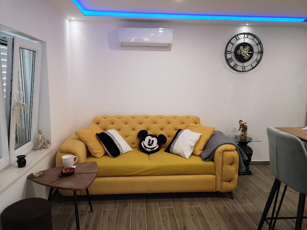 un sofá amarillo con almohadas en la sala de estar en Apartments Ella, en Split
