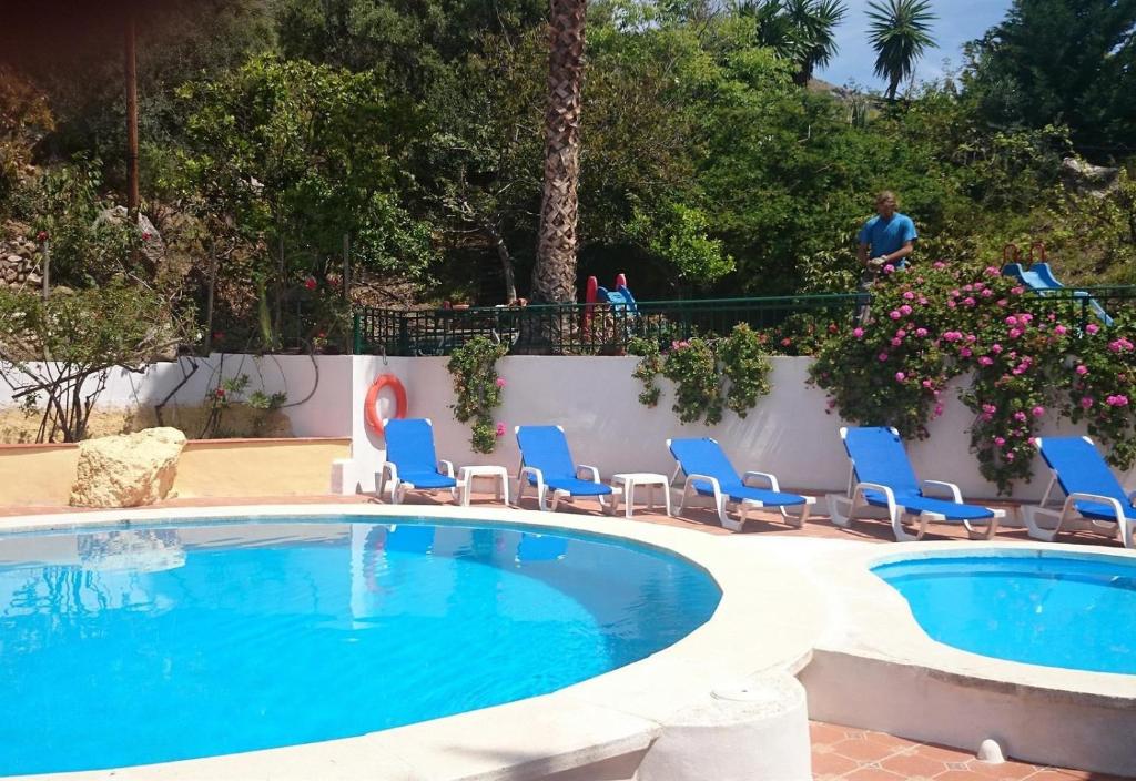 een zwembad met blauwe stoelen en bloemen bij Finca Santa Matilde Málaga in Málaga