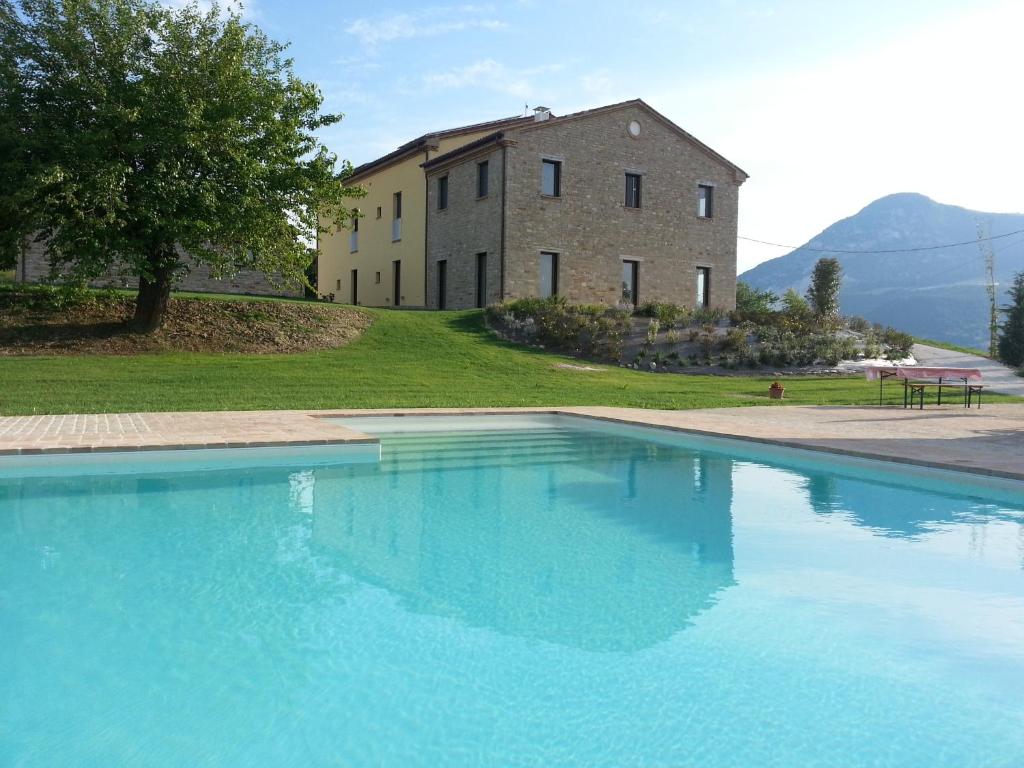 a large blue swimming pool in front of a building at Amico Country House in Serra San Quirico