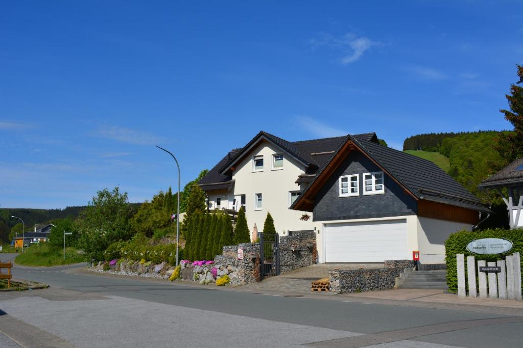 a white house with a black roof on a street at Kleines Glück in Willingen &MeineCardPlus in Willingen
