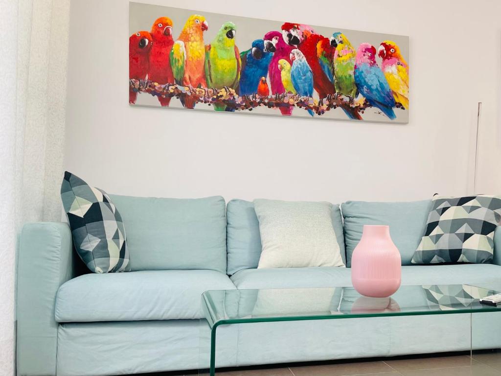a living room with a blue couch with parrots painting at Sunny Sanlucar in Sanlúcar de Barrameda