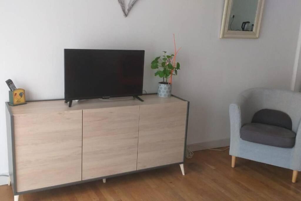 - une télévision sur une commode en bois avec une chaise dans l'établissement superbe appartement T3 traversant avec place de parking, à Rodez