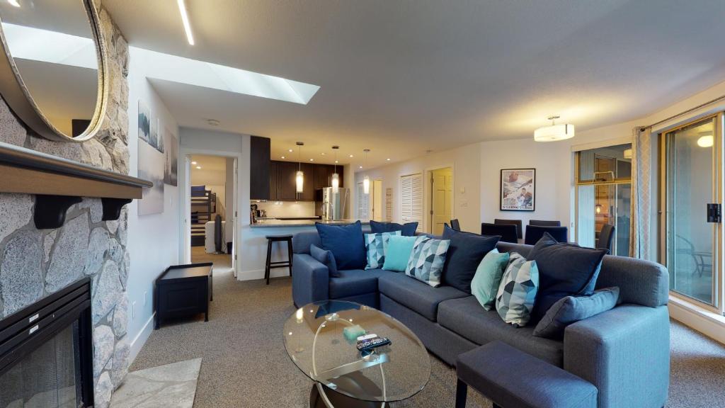 a living room with a blue couch and a fireplace at Modern Home with Forested Views by Harmony Whistler in Whistler