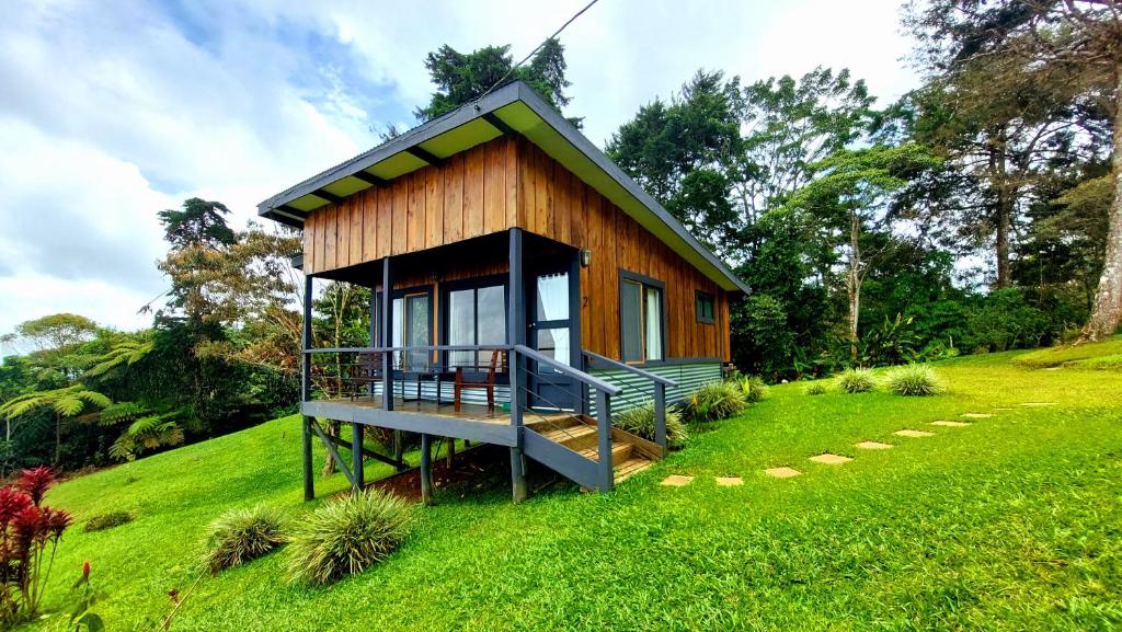 a small house on a hill with a green field at The Lodge at Reventazon River Mountain Ranch in Turrialba