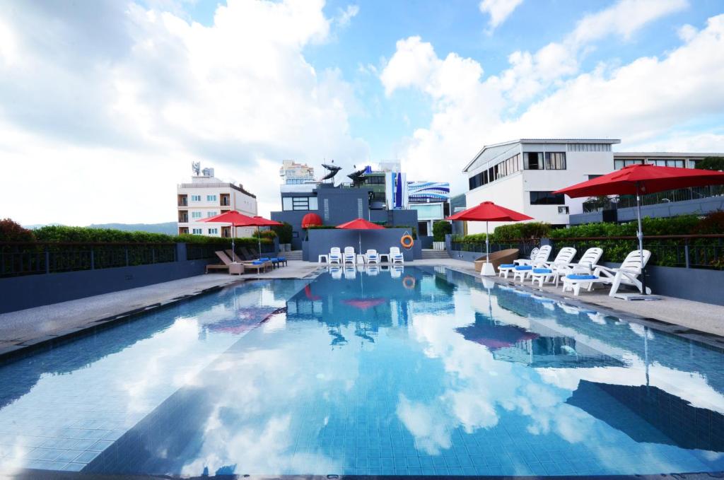 The Lantern Resorts Patong - SHA Extra Plus في شاطيء باتونغ: مسبح فيه كراسي ومظلات على مبنى