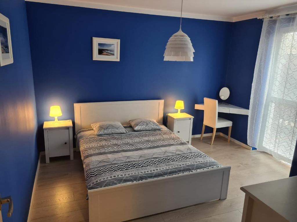 Wielicka Apartment 2 في كراكوف: غرفة نوم زرقاء مع سرير ومكتب