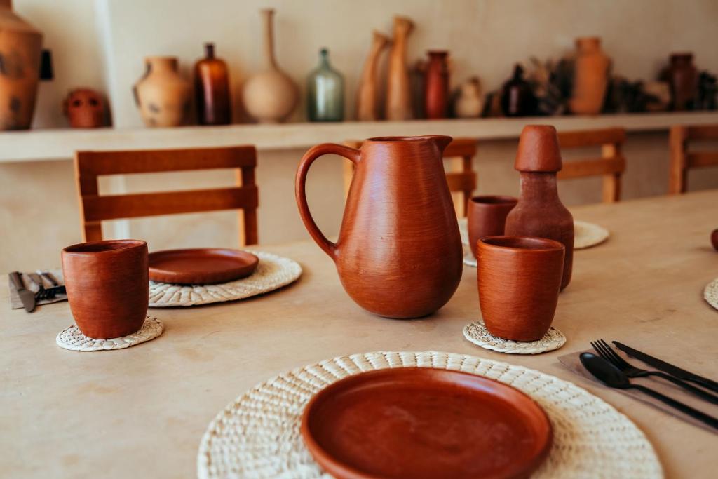 a table with brown vases and plates on it at Bajo las Hojas in Campeche