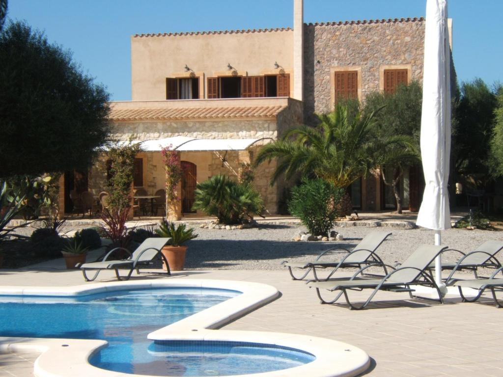 uma piscina com cadeiras e um edifício ao fundo em Finca S'olivar d'es Coscois em Santa Margalida