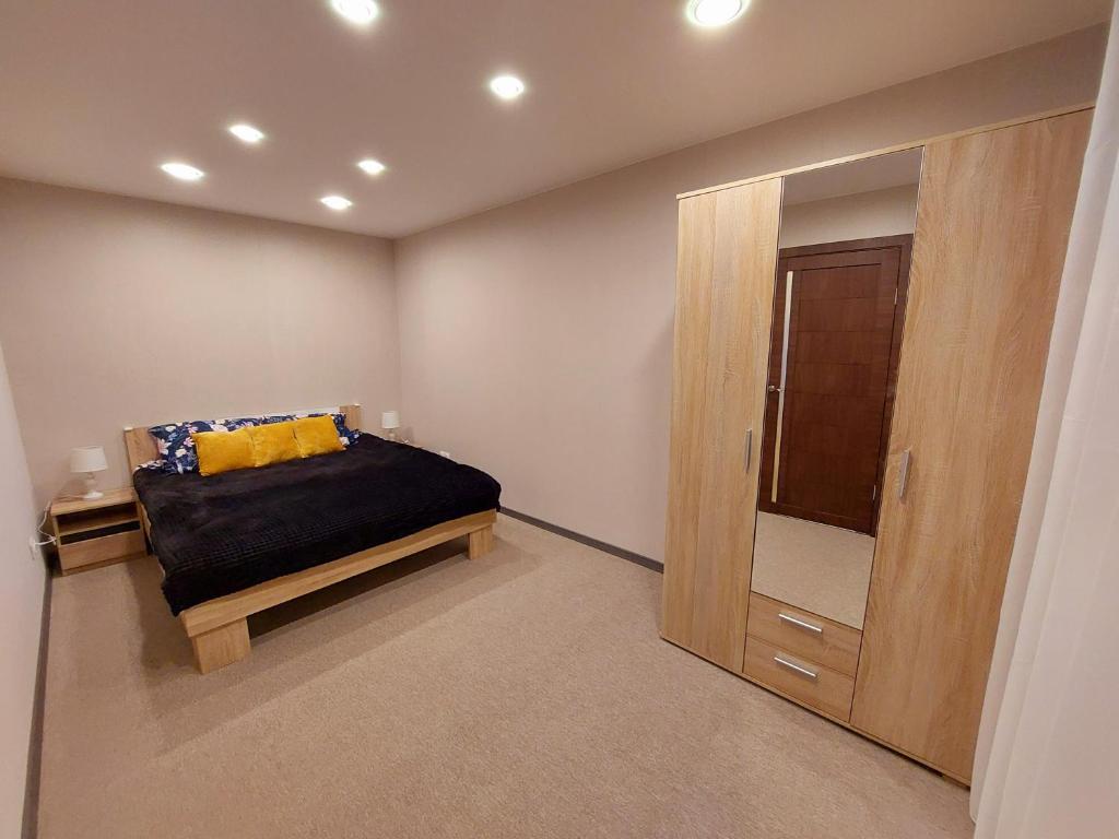 1 dormitorio con 1 cama y armario de madera en M14 Apartment en Gulbene