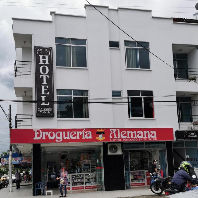a white building with a store with a red sign at hotel villa morenta in Yopal