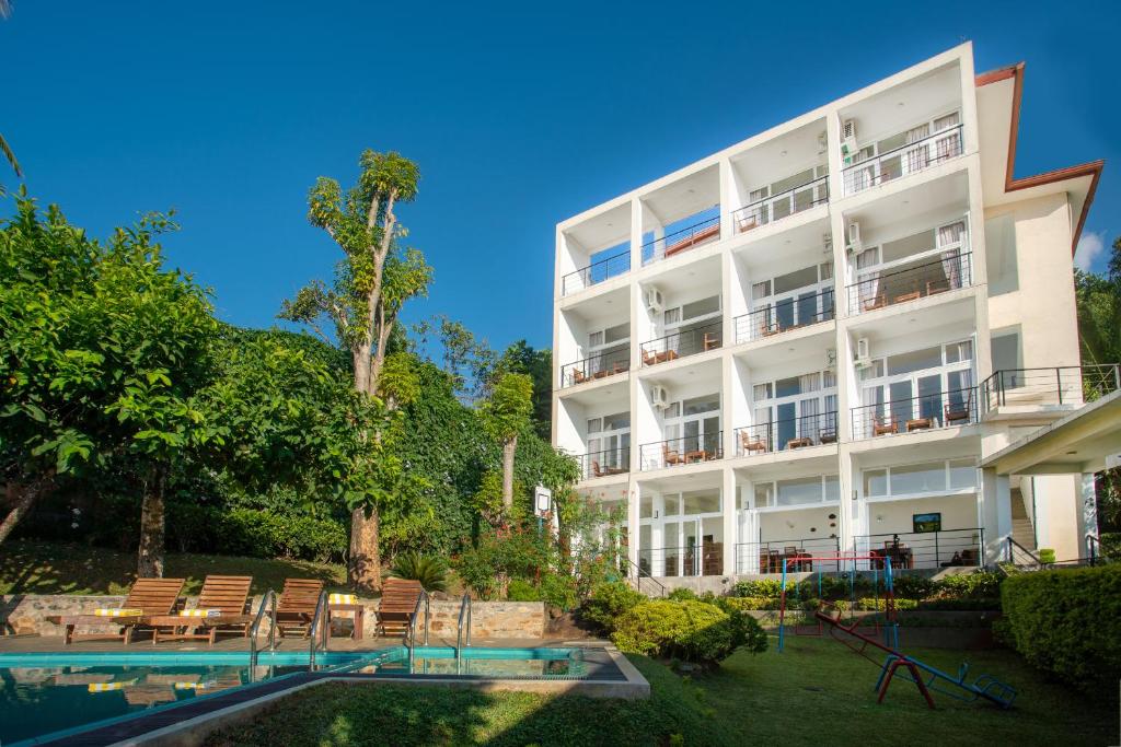 a large white building with a pool and chairs at The Kandyan Villa in Kandy