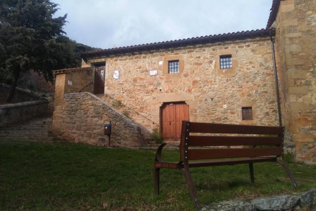 una panchina di fronte a un edificio in pietra con porta di Casa Rural El Silvestrito a Valdejeña