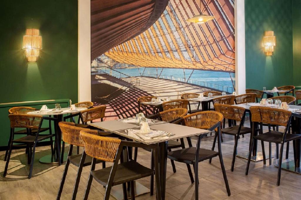 a dining room with tables and chairs and a mural at Best Western Plus Hôtel Belfort Centre Gare in Belfort