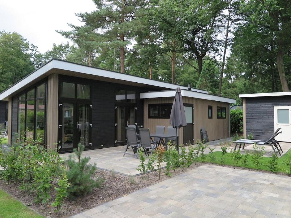 mały dom z patio i parasolem w obiekcie Nature-Connected Modern Stay w mieście Hoenderloo