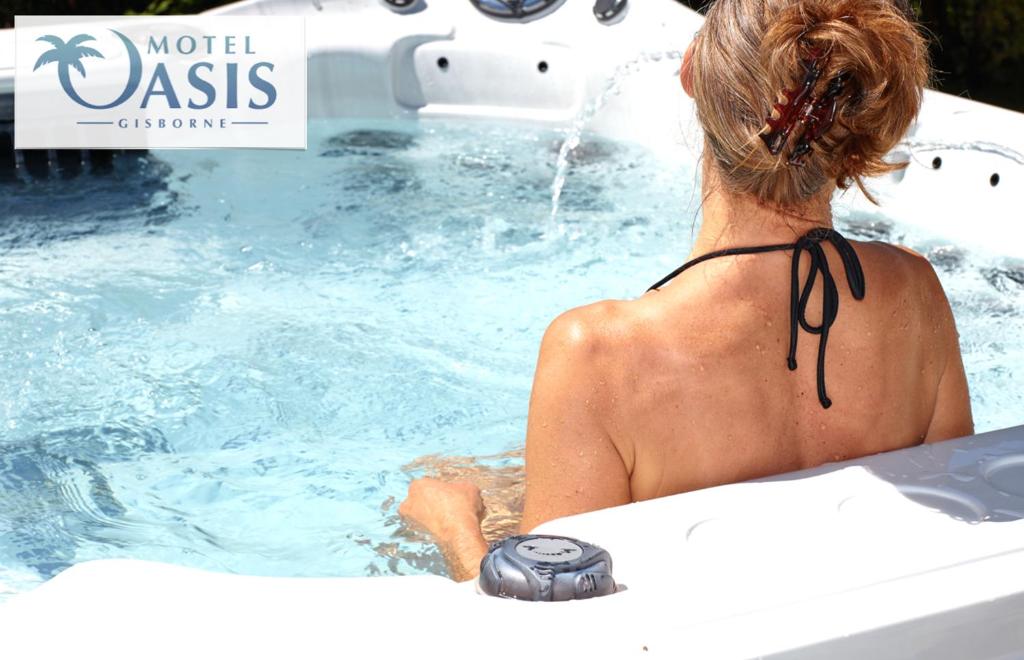 een vrouw zit in een zwembad bij Motel Oasis in Gisborne