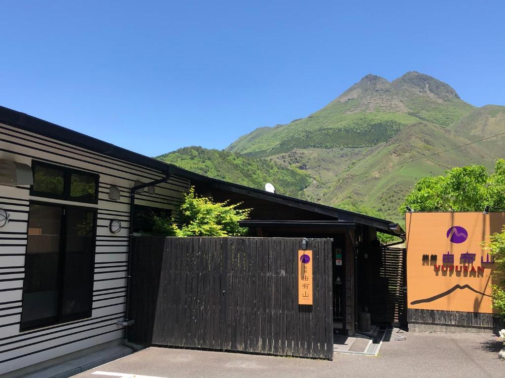 um edifício negro com uma montanha ao fundo em Ryokan Yufusan em Yufu