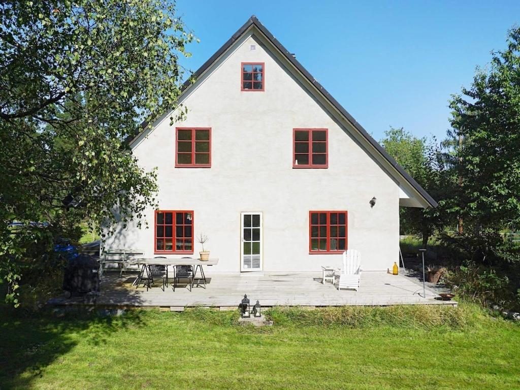 Biały dom z czerwonymi oknami i patio w obiekcie 7 person holiday home in DJURHAMN w mieście Djurhamn