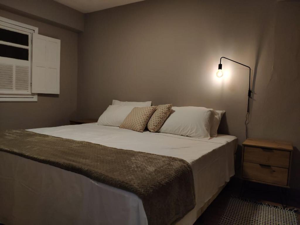 a bedroom with a large bed with white sheets and pillows at Aconchego do Pilar in Ouro Preto