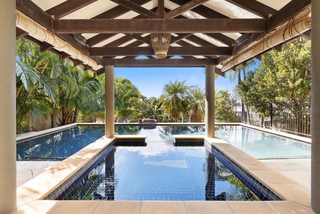 an outdoor swimming pool with a wooden pergola at Coolum OCEAN VIEWS, Oasis Pool, Cinema & Games Room in Coolum Beach