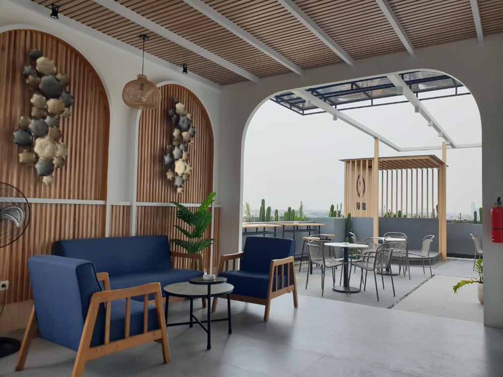 eine Lobby mit blauen Stühlen und Tischen sowie eine Terrasse in der Unterkunft Sambina Prime by Danapati in Jakarta
