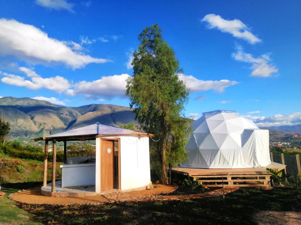 a geodesic dome house with a tree and mountains in the background at Amatea de Villa de Leyva in Villa de Leyva