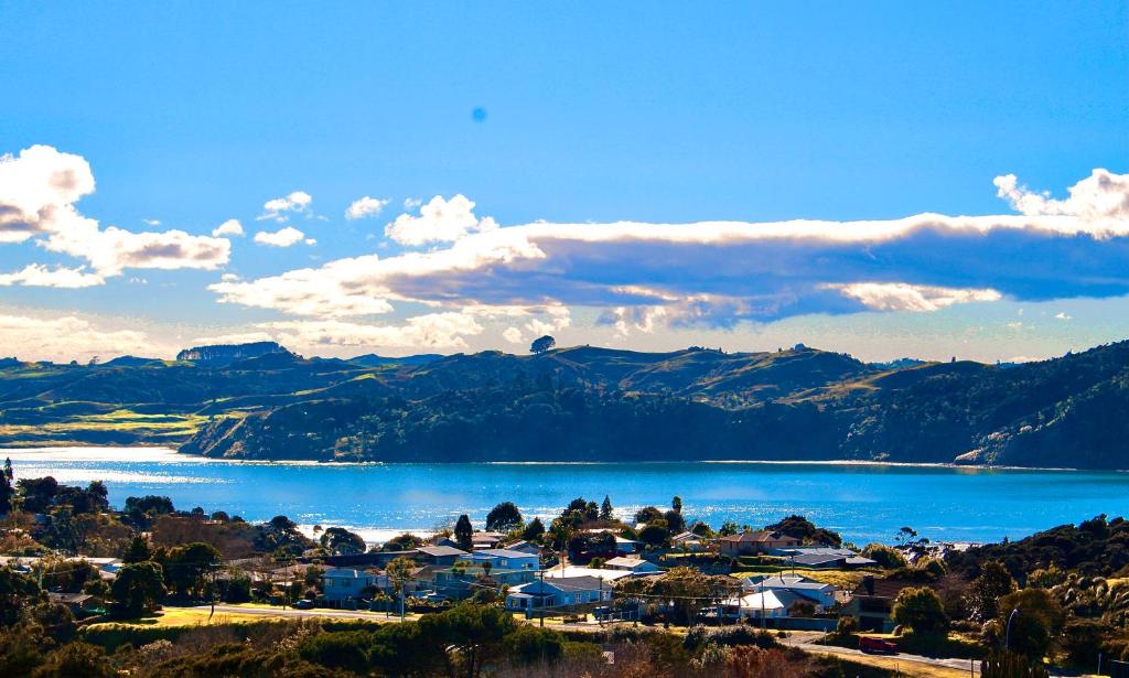 a view of a town and a lake with mountains at The Beach House on the Hill in Raglan