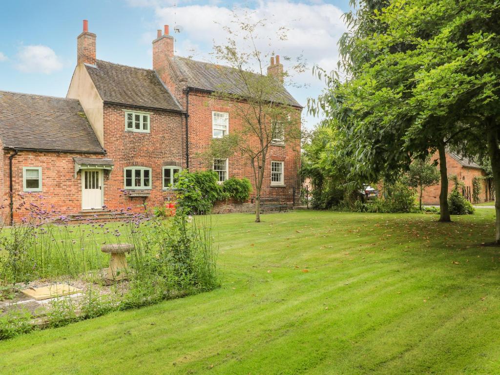 an old brick house with a grass yard in front of it at Mill Farm - The Farmhouse in Derby