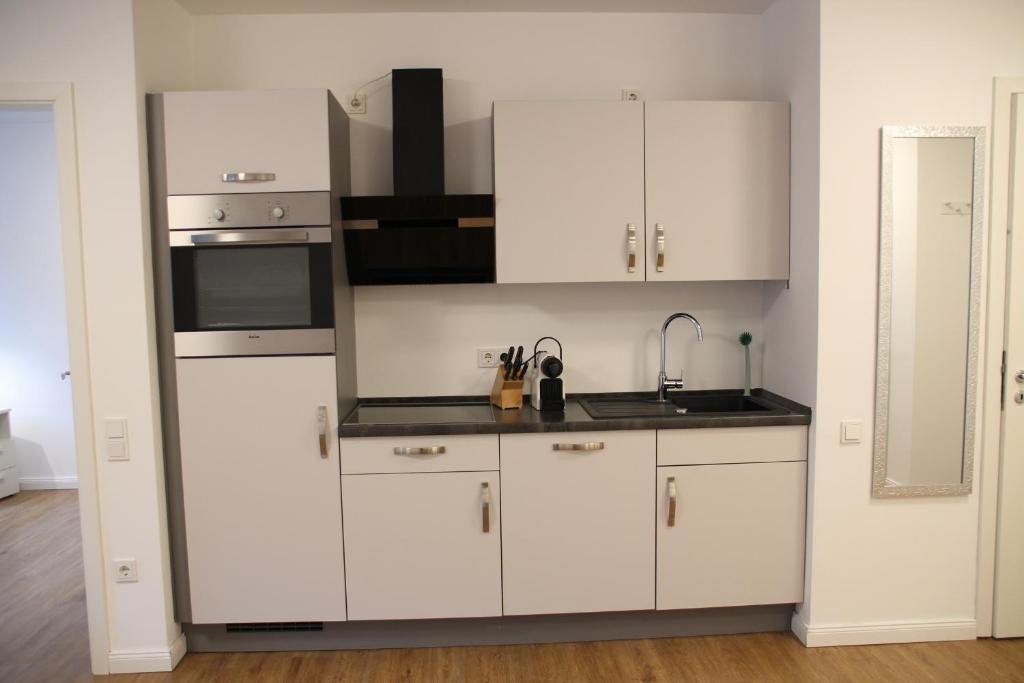 La cuisine est équipée de placards blancs et d'un four avec plaques de cuisson. dans l'établissement Casa Kronengarten Nr 2, à Hilden
