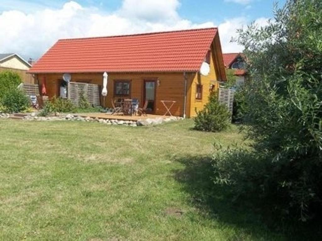 uma pequena casa com um telhado vermelho e um quintal em Ferienhaus Bliev-Hee Nr 3 em Klink