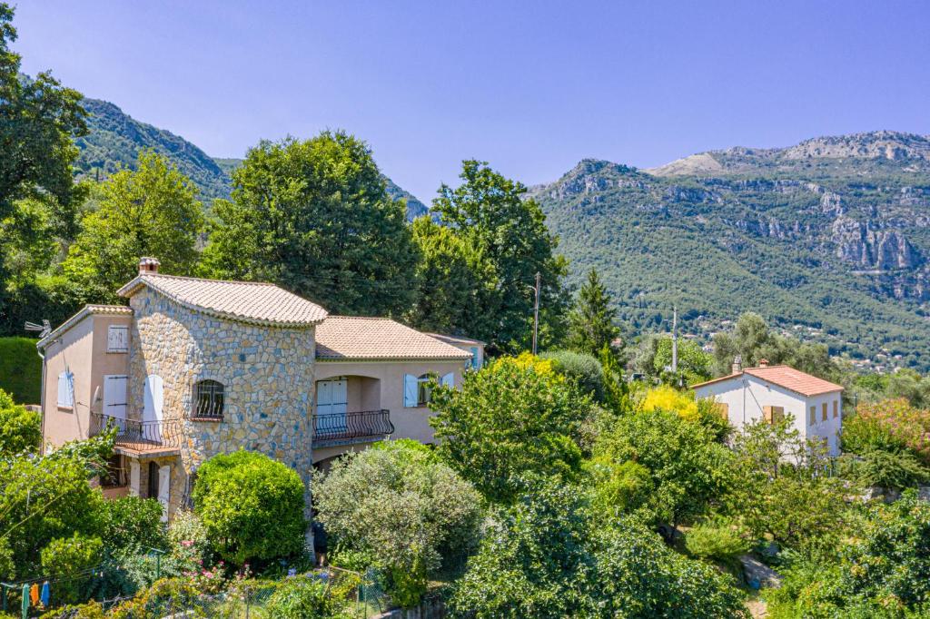 une maison sur une colline avec des montagnes en arrière-plan dans l'établissement Registered Accomodation 4 stars and 30mn Nice Cannes Antibes, à Le Bar-sur-Loup