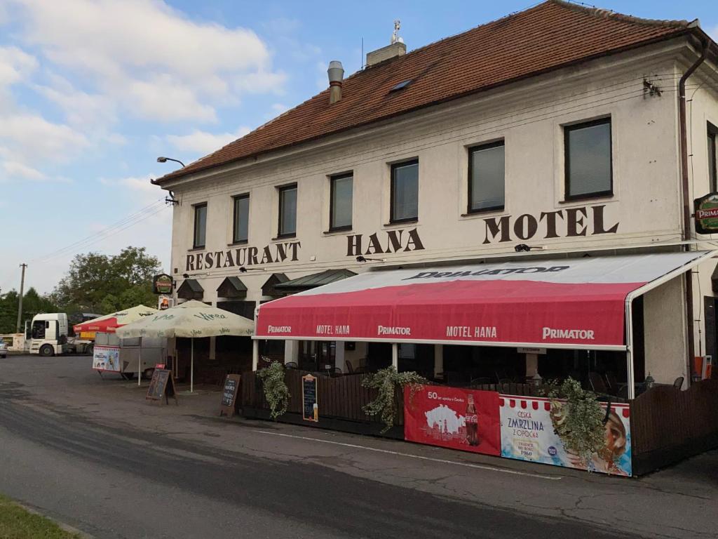 a building with a red awning next to a street at Restaurant Motel Hana Barbara Gastro sro in Ostřetín