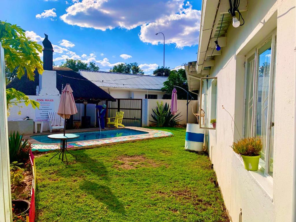 een achtertuin met een zwembad en een huis bij Kate's Nest Guesthouse in Windhoek