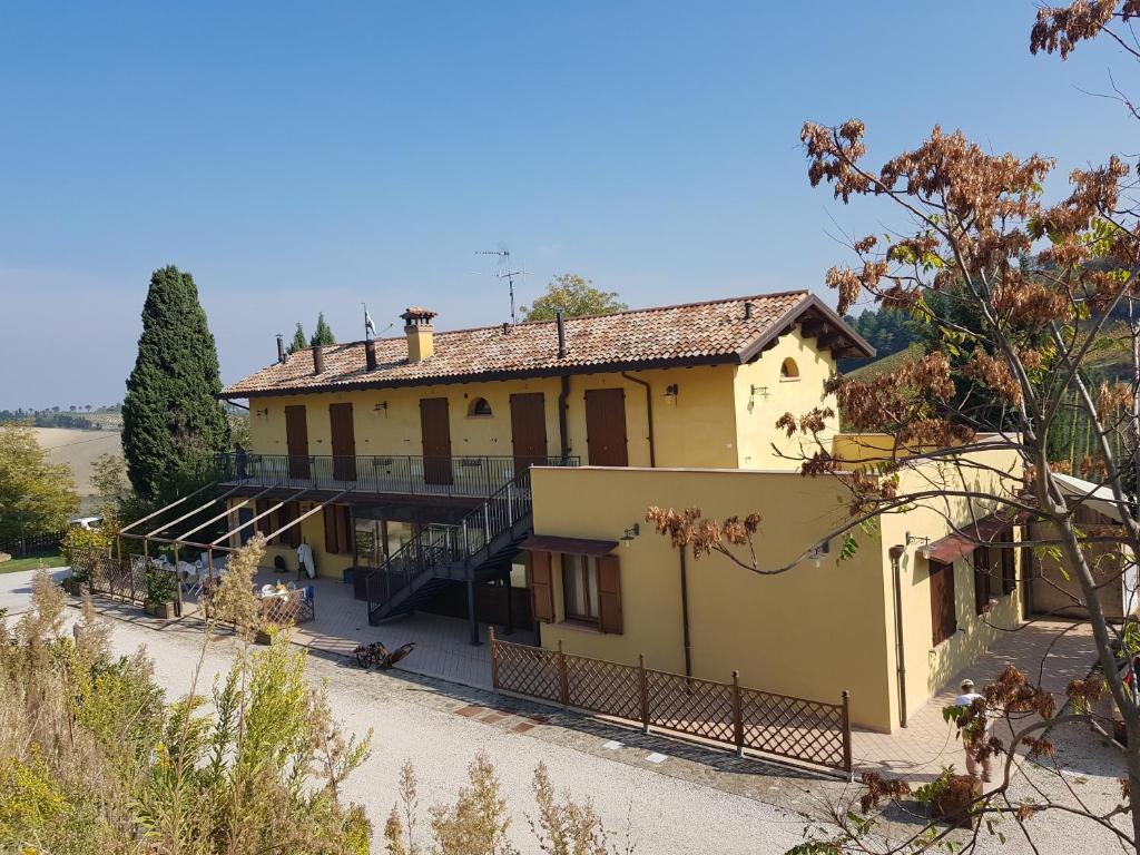 ein großes gelbes Haus mit einem Zaun davor in der Unterkunft Azienda agricola biologica Le Lucciole in Bertinoro