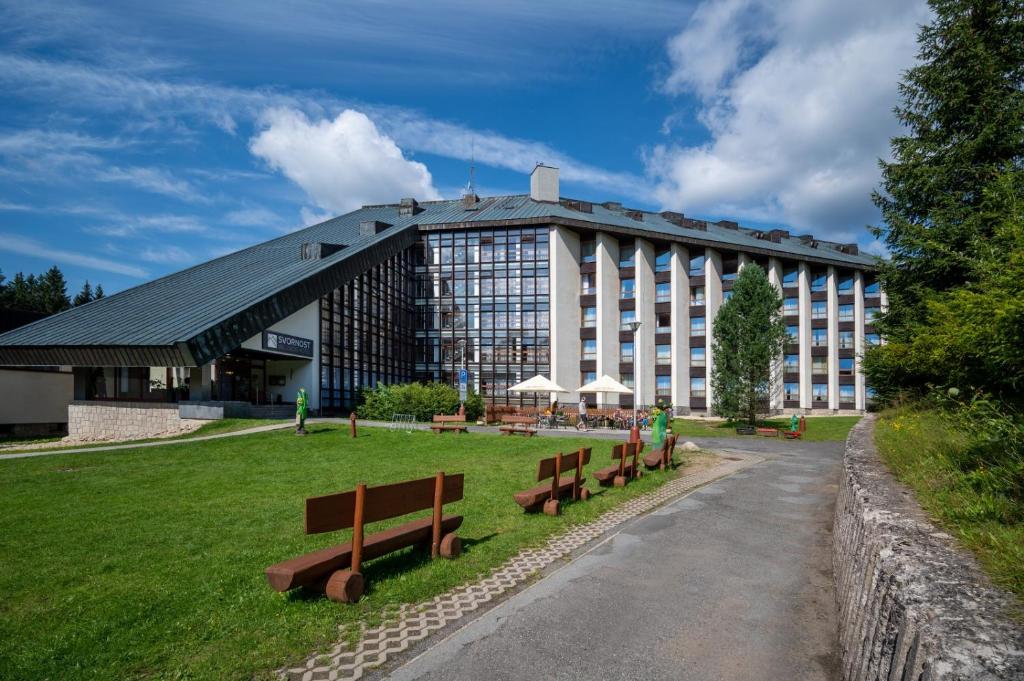 a large building with benches in front of it at Wellness Hotel Svornost in Harrachov