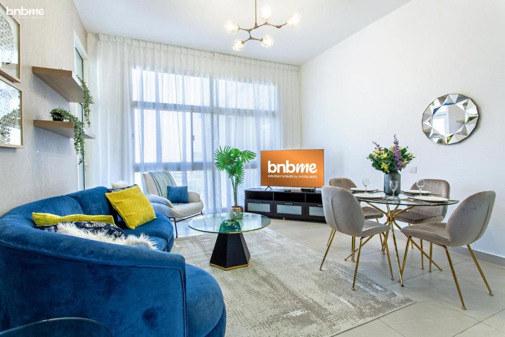 ein Wohnzimmer mit einem blauen Sofa und einem Tisch in der Unterkunft bnbmehomes - Elegant Apt In Al Barsha South - 613 in Dubai