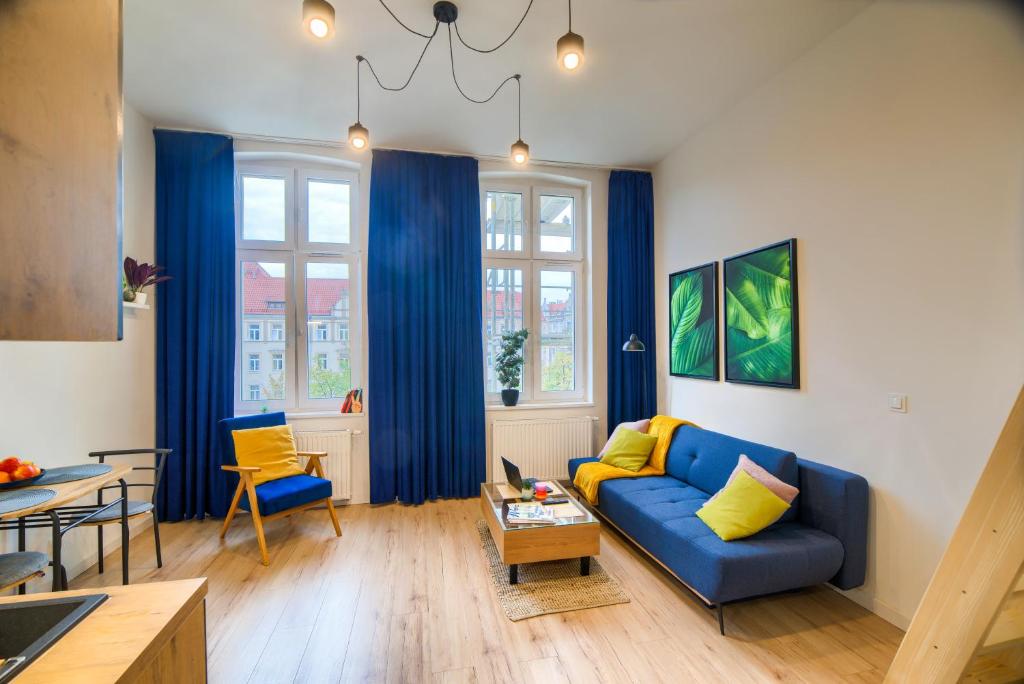 ein Wohnzimmer mit einem blauen Sofa und einem Tisch in der Unterkunft Tiny Studio City Centre / Mała Kawalerka in Stettin