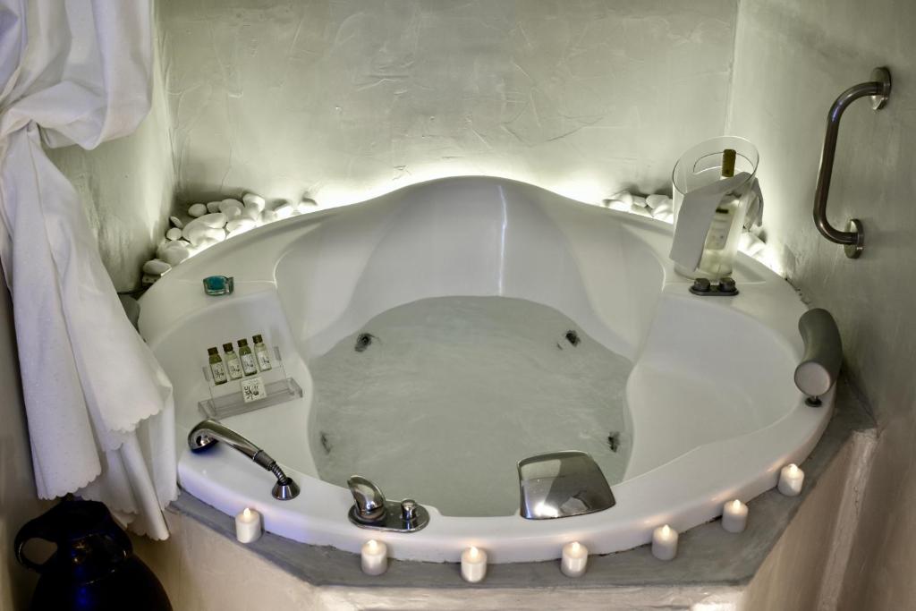 a bathroom with a bath tub with a sink at Aeolos Art & Eco Suites Adults Only in Imerovigli