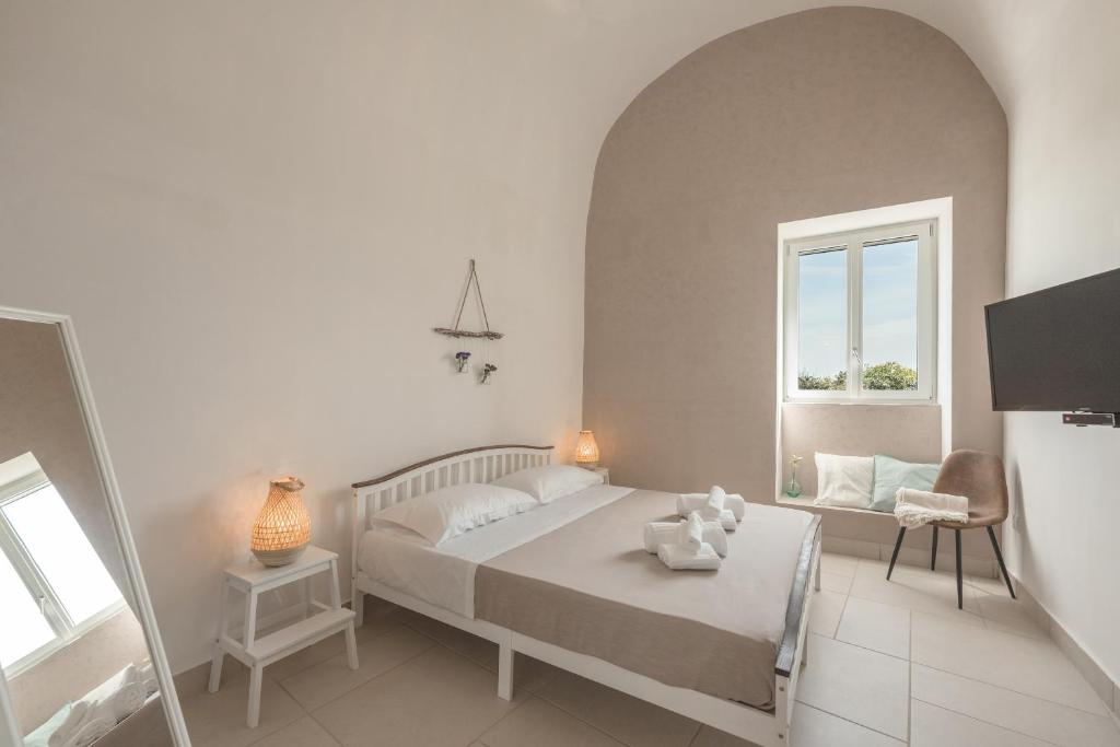 a white bedroom with a bed and a window at Cala Cala Rooms,Restaurant & Farm Experience in Procida