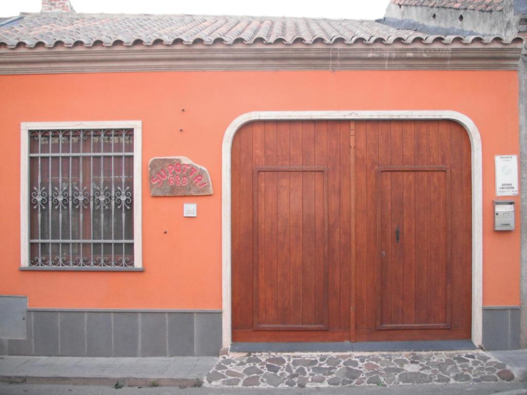 an orange building with a wooden door and a window at Bbsupottai in Càbras