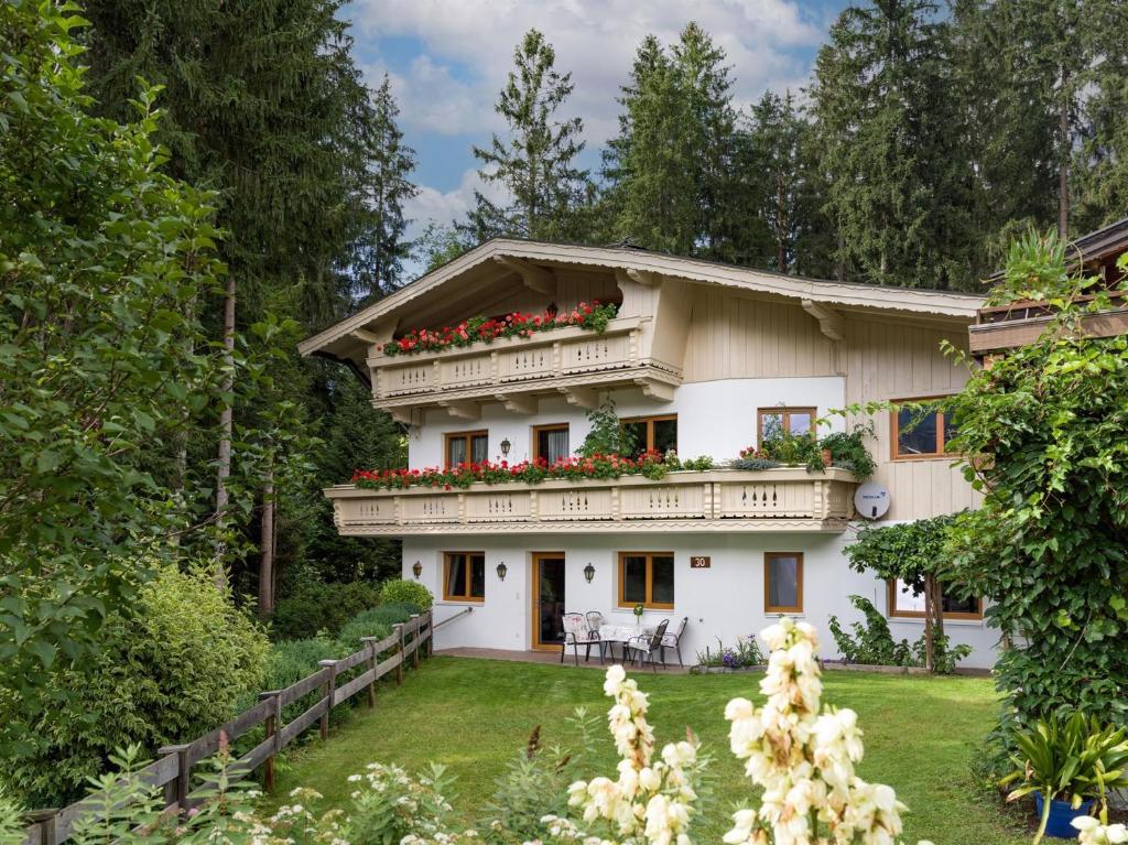 a house with a balcony with flowers on it at Haus am Waldesrand in Ellmau