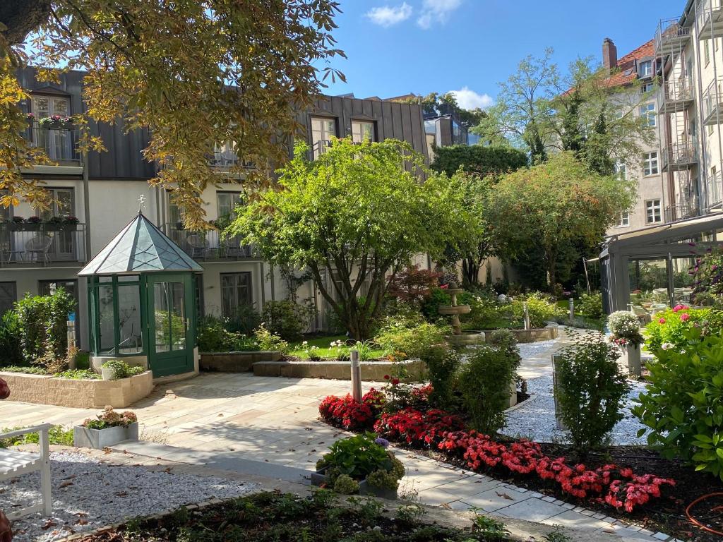 a garden in front of a building with a gazebo at MAXIMILIAN MUNICH Apartments & Hotel in Munich