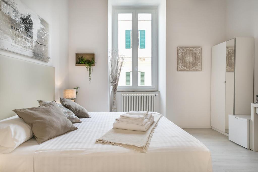 a white bedroom with a large white bed and a window at White Ostilia Guesthouse in Rome