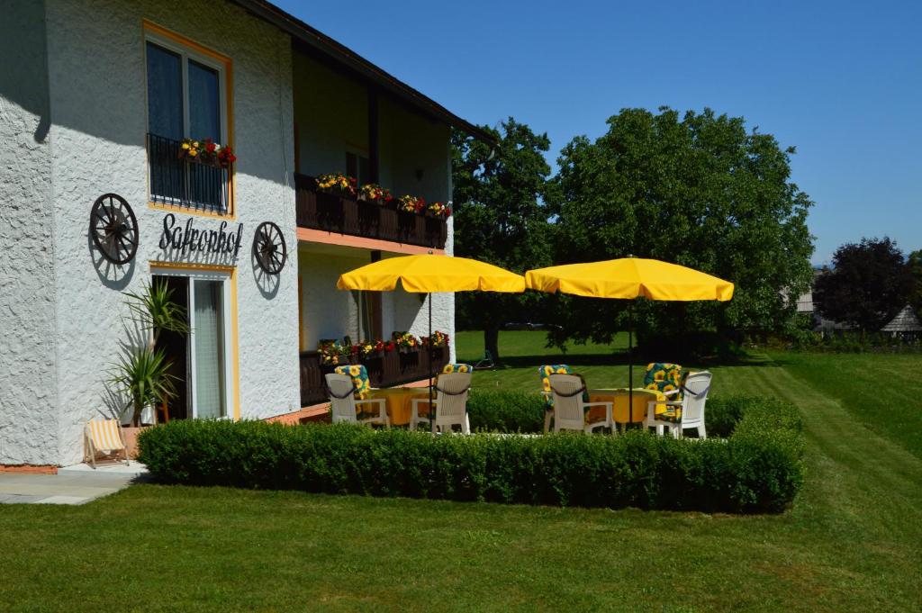 eine Gruppe von Stühlen und Sonnenschirmen vor einem Gebäude in der Unterkunft Safronhof in Reifnitz