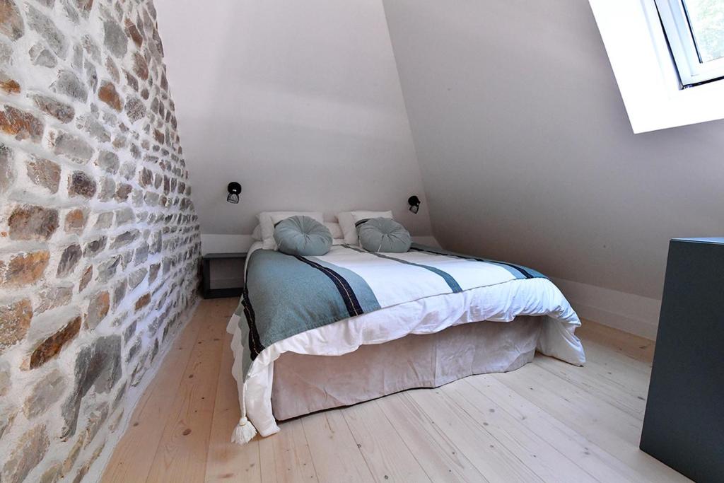 a bedroom with a bed and a stone wall at Le kocon, dans un écrin, le calme à la mer in Saint-Pair-sur-Mer