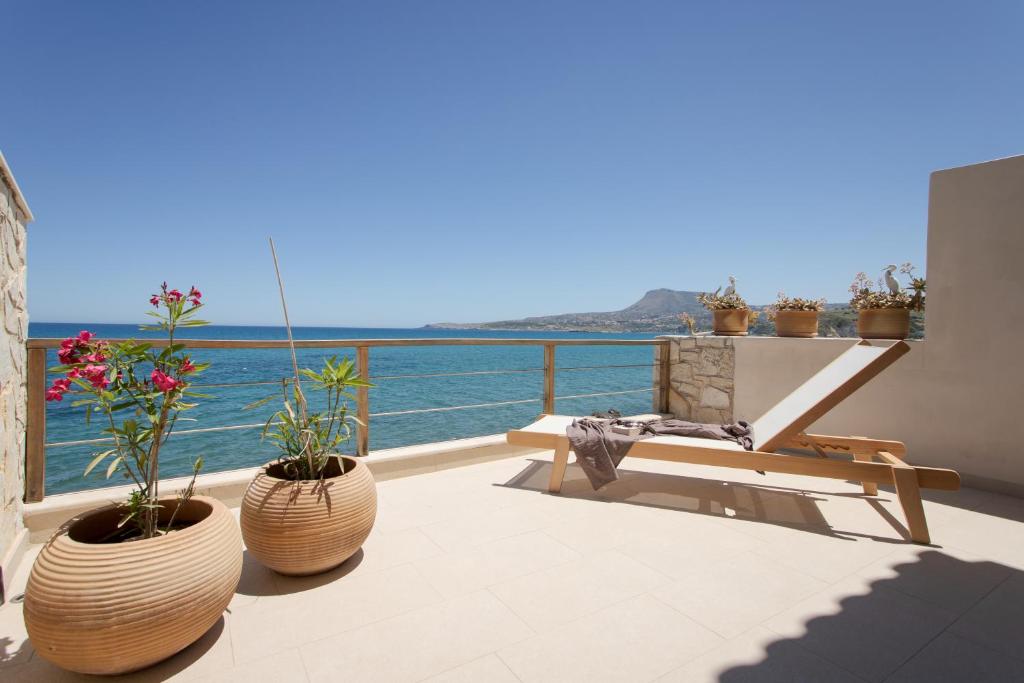 a balcony with a bench and flowers and the ocean at Blue Dream Villa Kalyves in Kalyves