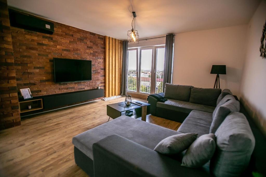 ein Wohnzimmer mit einem Sofa und einem TV in der Unterkunft Apartman PAOLA in Slavonski Brod