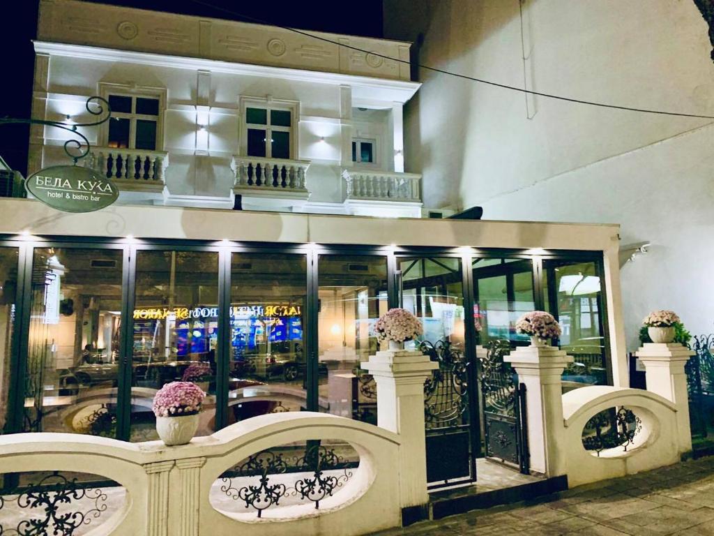 una tienda frente a un edificio con ventanas y flores en Bela Kuka Hotel, en Bitola